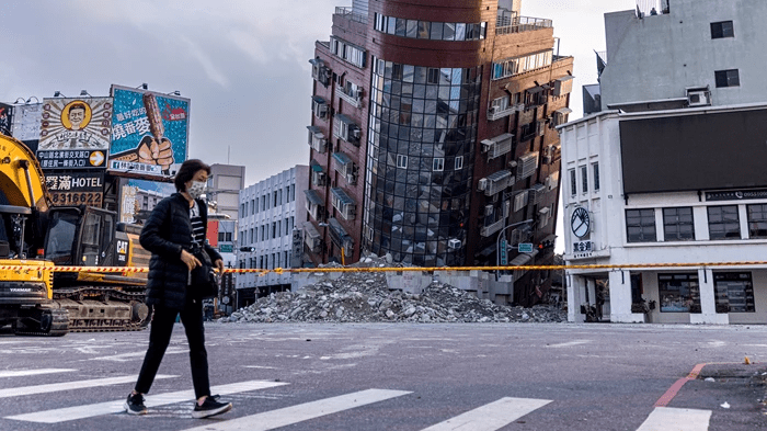 地震過後，路人經過一棟受損建築。