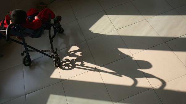 A boy basks in the sunlight from a window at an orphanage for disabled children in China