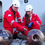 Two archaeologists examine ancient jars from shipwreck