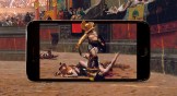 A gladiator standing over some men that he's killed in a phone with a crowd in the background